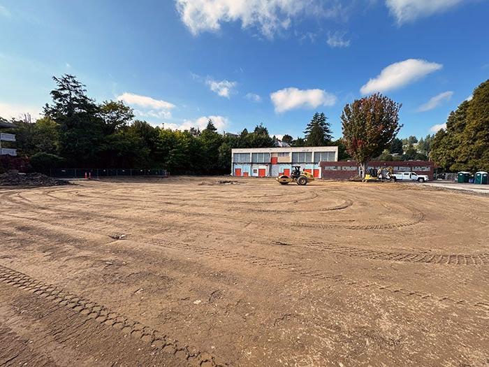 a graded dirt field in front of a two story building